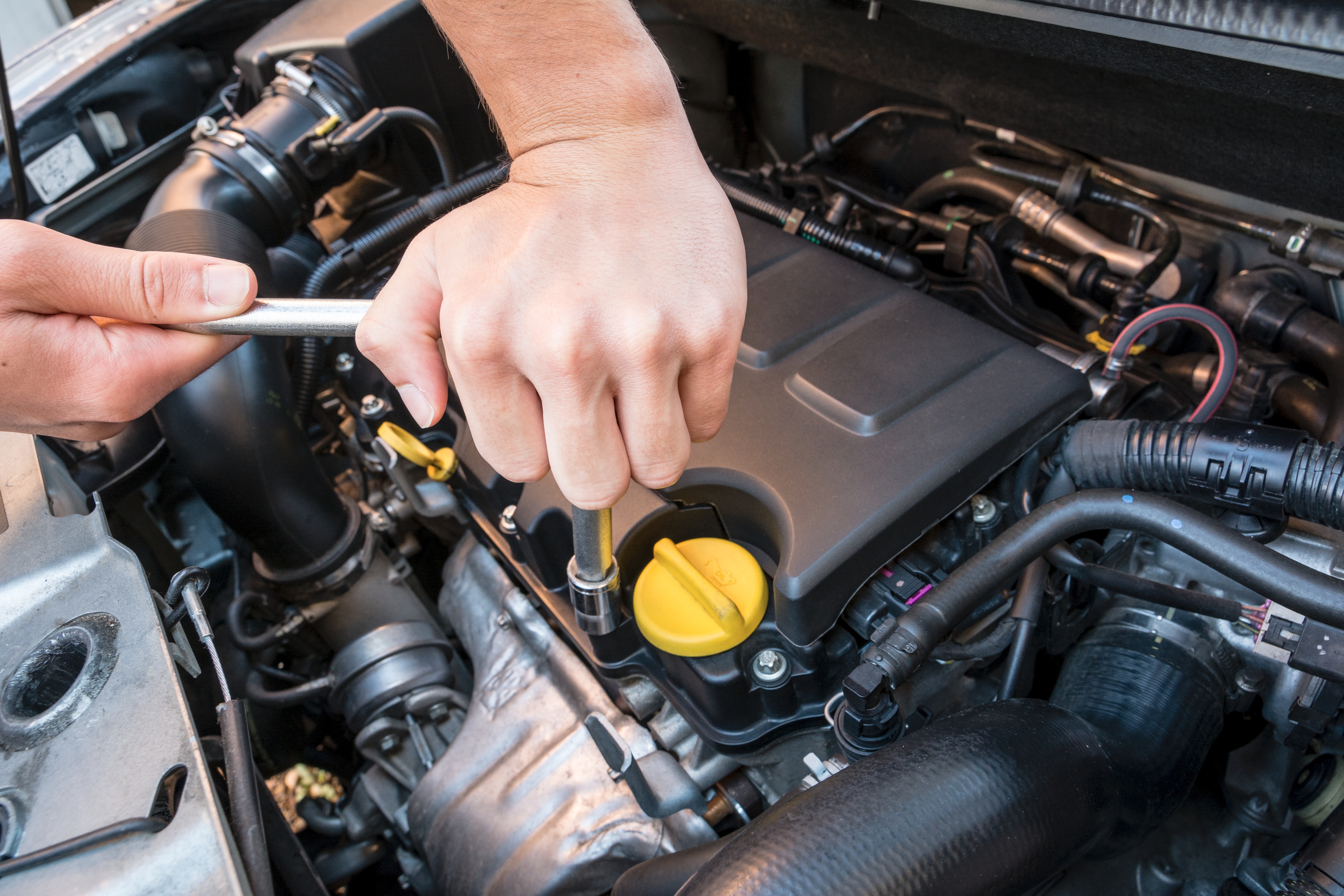 Hands repairing a modern car engine with a wrench